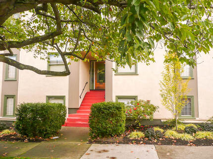 Entrance to building with red cement stairs leading to doorway